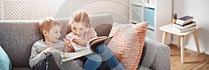 Cute children sitting on the soft sofa and reading books