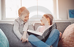 Cute children sitting on the soft sofa and reading books