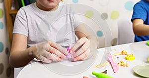 Cute children sitting at the table and plays with playdough