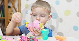 Cute children sitting at the table and plays with playdough