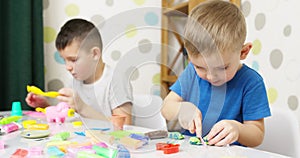 Cute children sitting at the table and plays with playdough