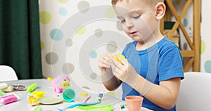 Cute children sitting at the table and plays with playdough