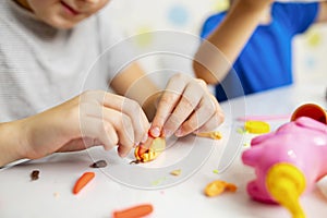 Cute children sitting at the table and plays with playdough