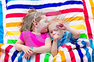 Cute children sleeping under colorful blanket
