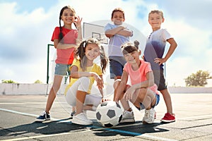 Cute children with soccer ball at sports court on sunny day. Summer camp