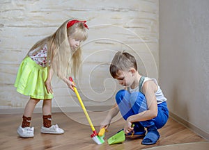 Cute children using toy broom and dustpan