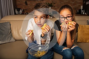 Cute children watching movie on TV on sofa