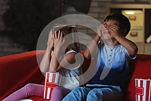 Cute children watching TV on sofa in evening