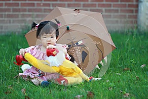 Cute Chinese baby girl play plush toy on the lawn