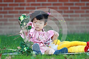 Cute Chinese baby girl play plush toy on the lawn