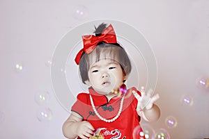 Cute Chinese little baby in red cheongsam play soap bubbles