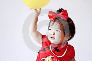 Cute Chinese little baby in red cheongsam play yellow balloon