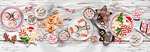 Cute Christmas sweets and cookie table scene on a rustic white wood banner background