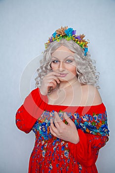 Cute chubby girl with flowers in white curly hair in red rustic dress