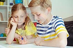 Cute clever schoolchildren are came back to school and studying together at the table