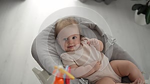 Cute close-up of baby lying in cradle and holding teething ring, adorable baby 5 month old baby