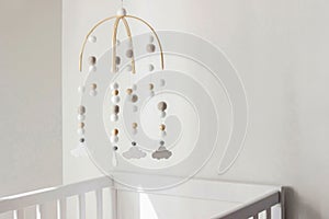 Cute cloud mobile hanging on crib in nursery room