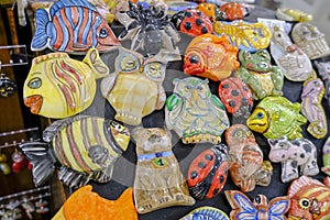 Cute colorful ceramic owls, fishes, bugs toys of different sizes close-up. souvenir shop in the market