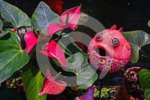 Cute colorful fish statue and Red anthurium flowes ( tailflower, flamingo flower, laceleaf ) decoration in the garden