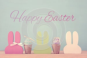 Cute colorful wooden bunny ears and easter eggs over wooden table.