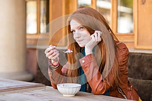 Cute content woman having breakfast and talking on cellphone