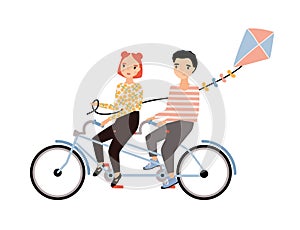 Cute couple dressed in trendy clothes riding tandem bicycle and holding kite. Young man and woman sitting on bike