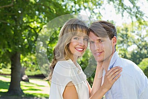 Cute couple hugging and smiling at camera in the park