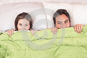 Cute couple lying in bed under the covers