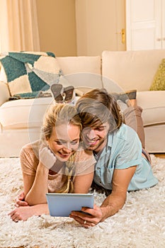 Cute couple lying on the carpet using tablet