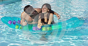 Cute couple relaxing on floating mattress in pool