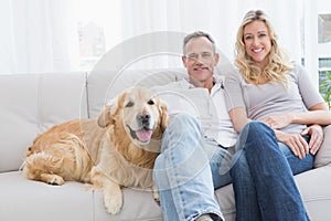 Cute couple relaxing together on the couch with their dog