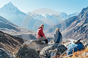 Cute Couple resting on the Everest Base Camp trekking route near Dughla 4620m. Man smiling to woman.Backpackers left Backpacks and