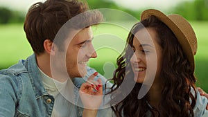 Cute couple sitting on meadow. Happy man and woman laughing outdoors