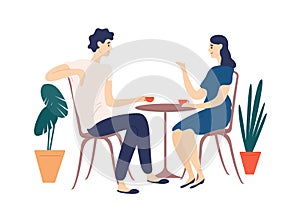 Cute couple sitting at table, drinking tea or coffee and talking. Young funny man and woman at cafe on date. Dialog or