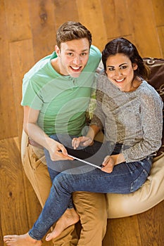 Cute couple using tablet pc on beanbag