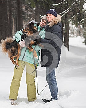 Cute couple walking and having fun with their dog in winter forest