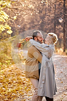 cute couple is walking in park at autumn leaf fall, resting in nature together. leisure.
