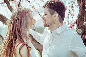 Cute couple watch on each other in blooming apple garden