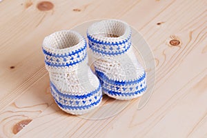 Cute Crochet baby booties on wooden background