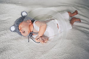 Cute crying newborn little baby boy sleeping in crib in a knitted suit with ears. Baby goods packaging template. Healthy child,