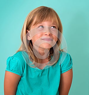 Cute cunning little girl isolated on turquoise background. Human emotion facial expression.