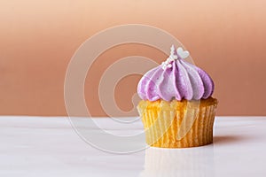 Cute cupcake with small white heart on purple cream on pink background