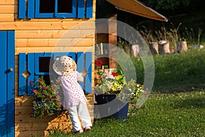 Cute curios girl looking into wooden playhouse in the garden