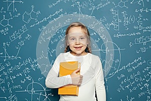 Cute curiosity little girl mathematics student on blue school background with hand drawings science formula pattern.