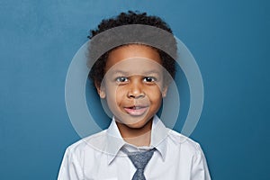 Cute curious African American child schoolboy student 6 years old on blue backgroung. Black kid boy portrait