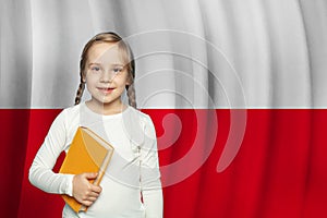 Cute curious little school girl against Polish flag background. Education in Poland concept