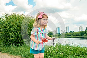 Cute curly baby girl eating watermelon candy in a sunny park. baby with outdoors lollipop