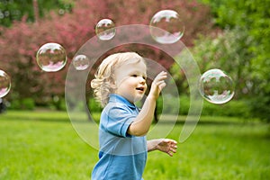 Cute curly baby with soap bubbles. children playing