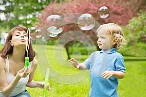 Cute curly baby with soap bubbles. children playing