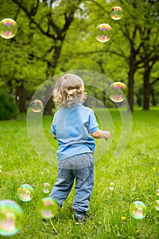 Cute curly baby with soap bubbles. children playing